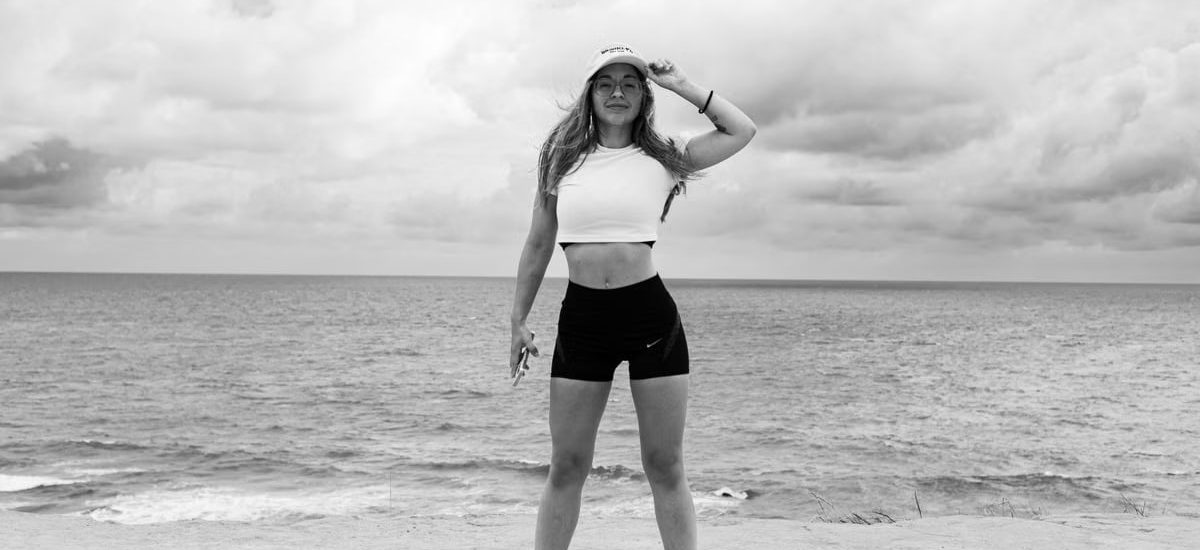 Black and white photo of a woman standing at the beach in Natal, Brazil, enjoying the ocean view.