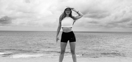 Black and white photo of a woman standing at the beach in Natal, Brazil, enjoying the ocean view.